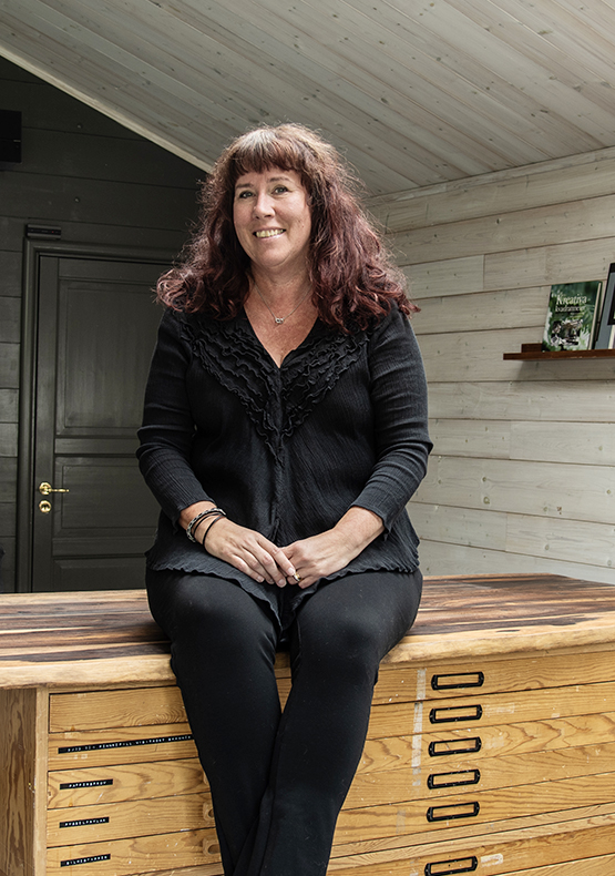 Designern Mari Forsell sittandes på en bänk i sin ateljé